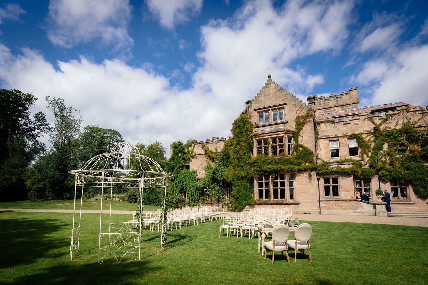 Panoramic view of a countryside wedding venue with stone architecture and outdoor ceremony space. Ellingham Hall