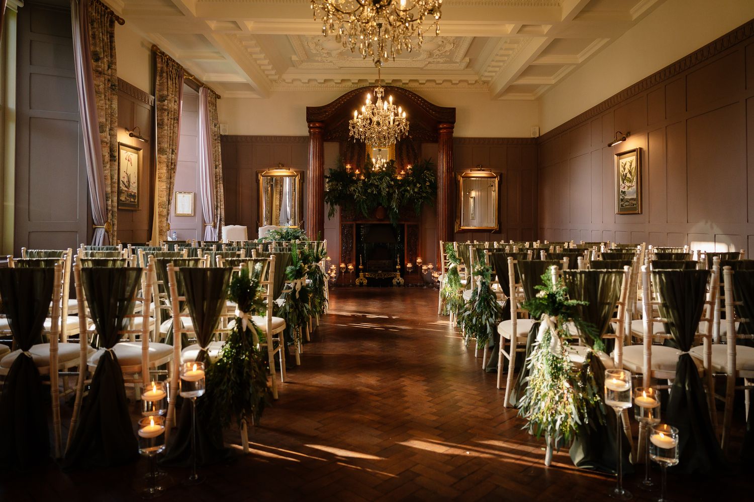 Grand ballroom setup with crystal chandeliers, ambient lighting, and rows of elegant table settings. Ellingham Hall