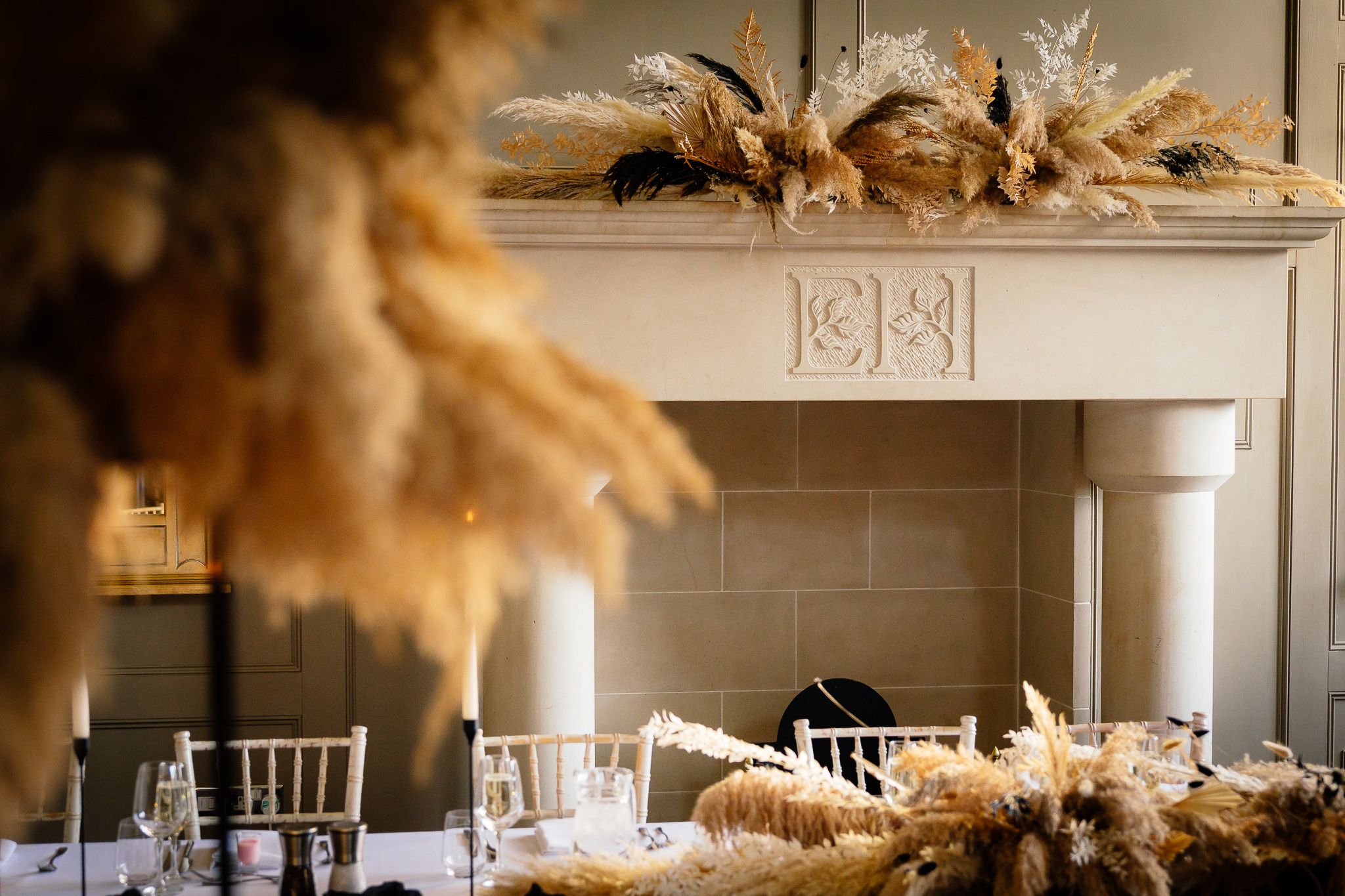 Elegant wedding reception room with pampas grass centerpieces and neutral decor. Ellingham Hall
