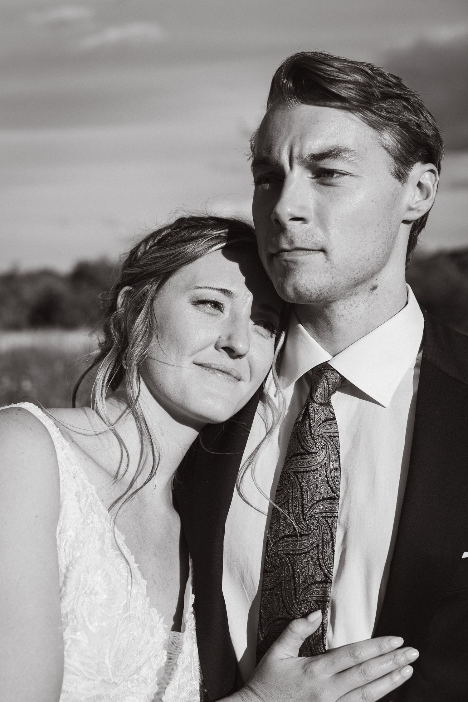 Black and white portrait of newlyweds sharing an intimate moment outdoors.