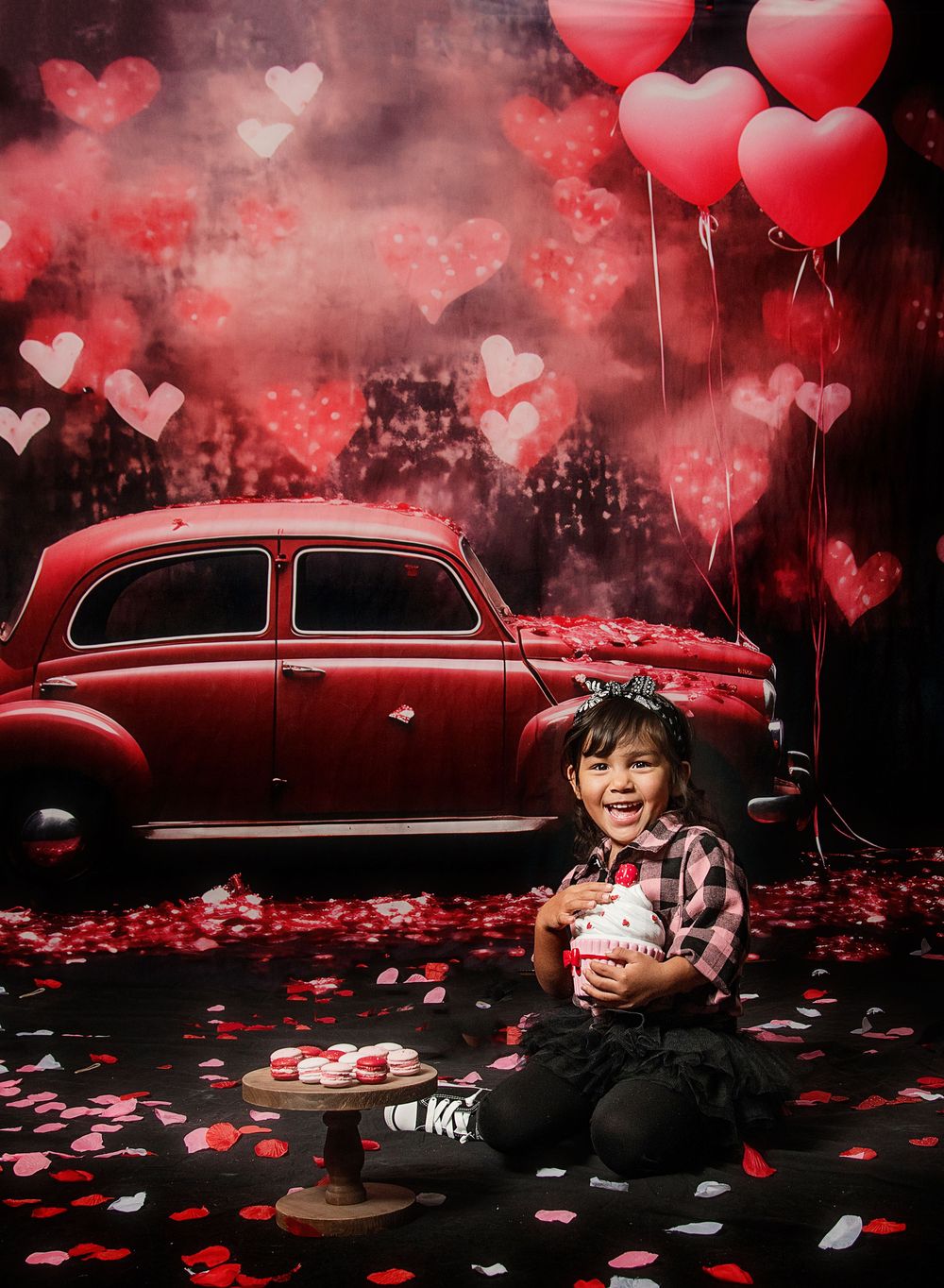 Red heart balloons and rose petals create a romantic Valentine's Day scene with a vintage car in moody lighting.