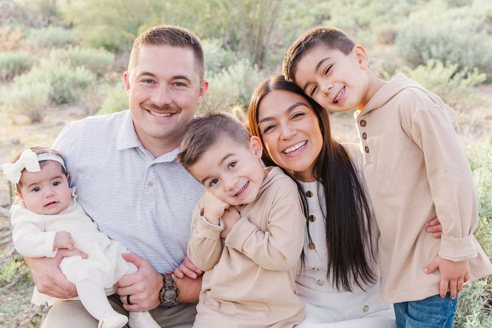 Light and airy family portrait of two parents and three young kids smiling in a group hug in the Mesa, AZ desert.