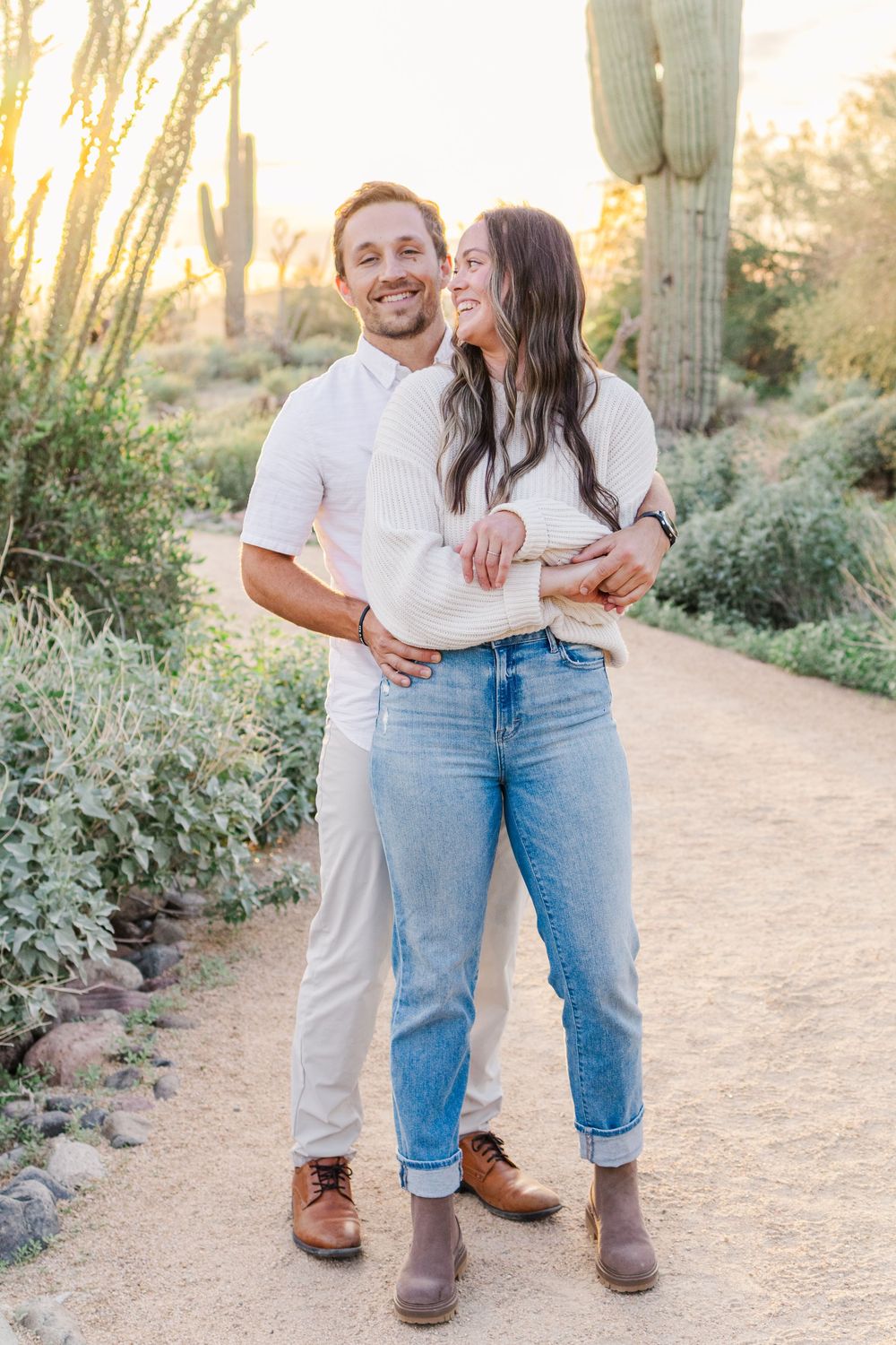 Golden hour portrait of young married couple smiling at each other in the Mesa, Arizona desert.
