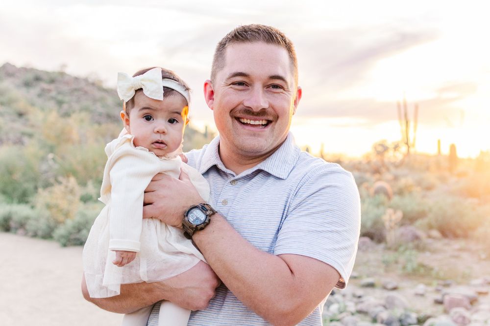 Portrait of young dad with infant daughter smiling during golden hour in the desert at Usery Mountain Regional Park.
