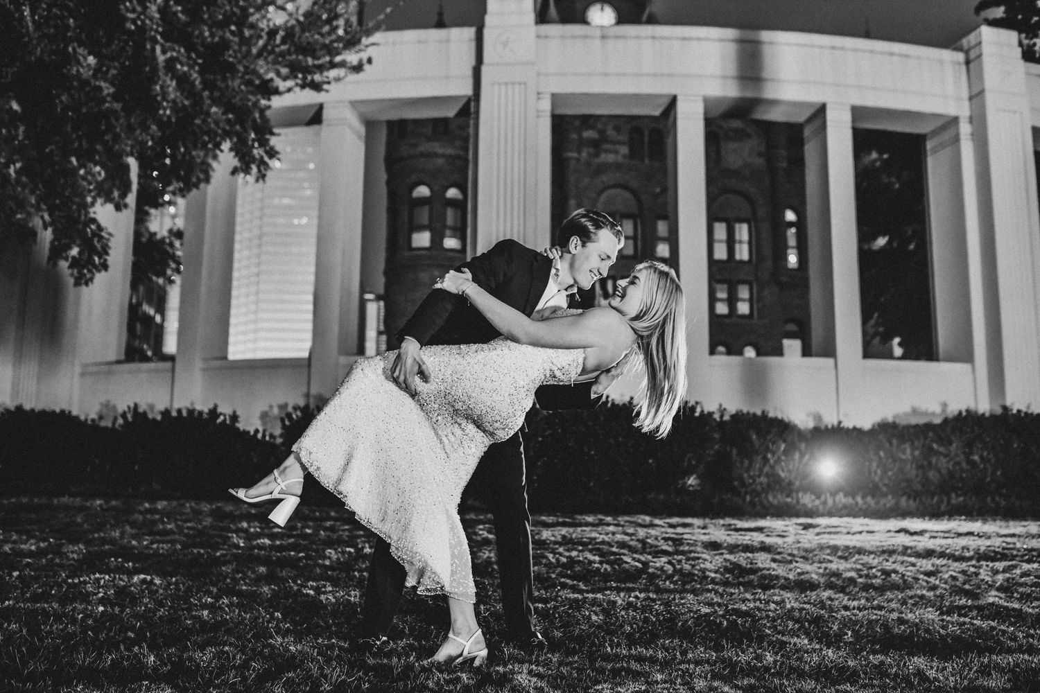 Newly engaged couple sharing a dramatic dip in downtown Dallas at sunset