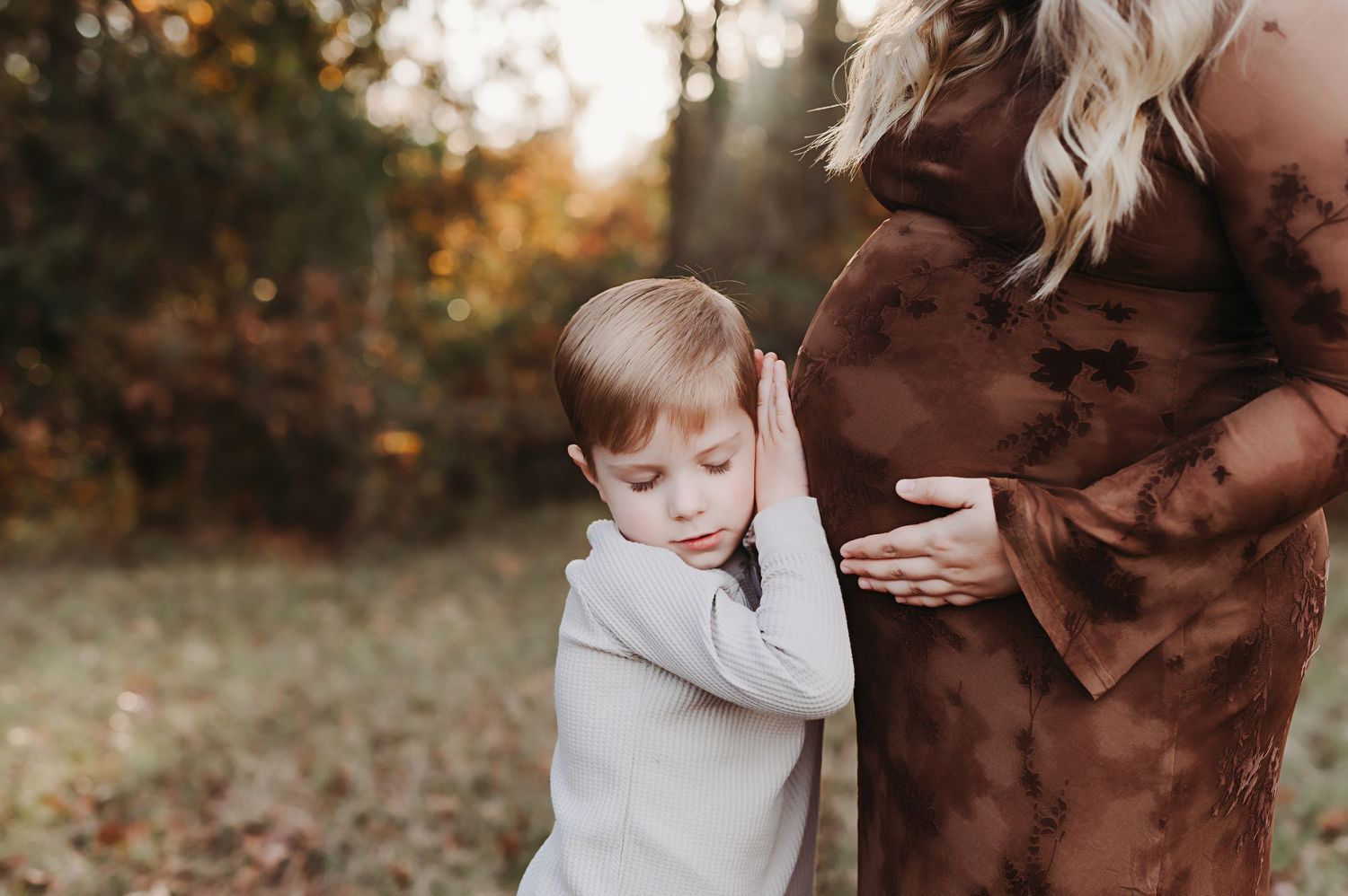 Little boy listening to his moms belly to hear the baby.