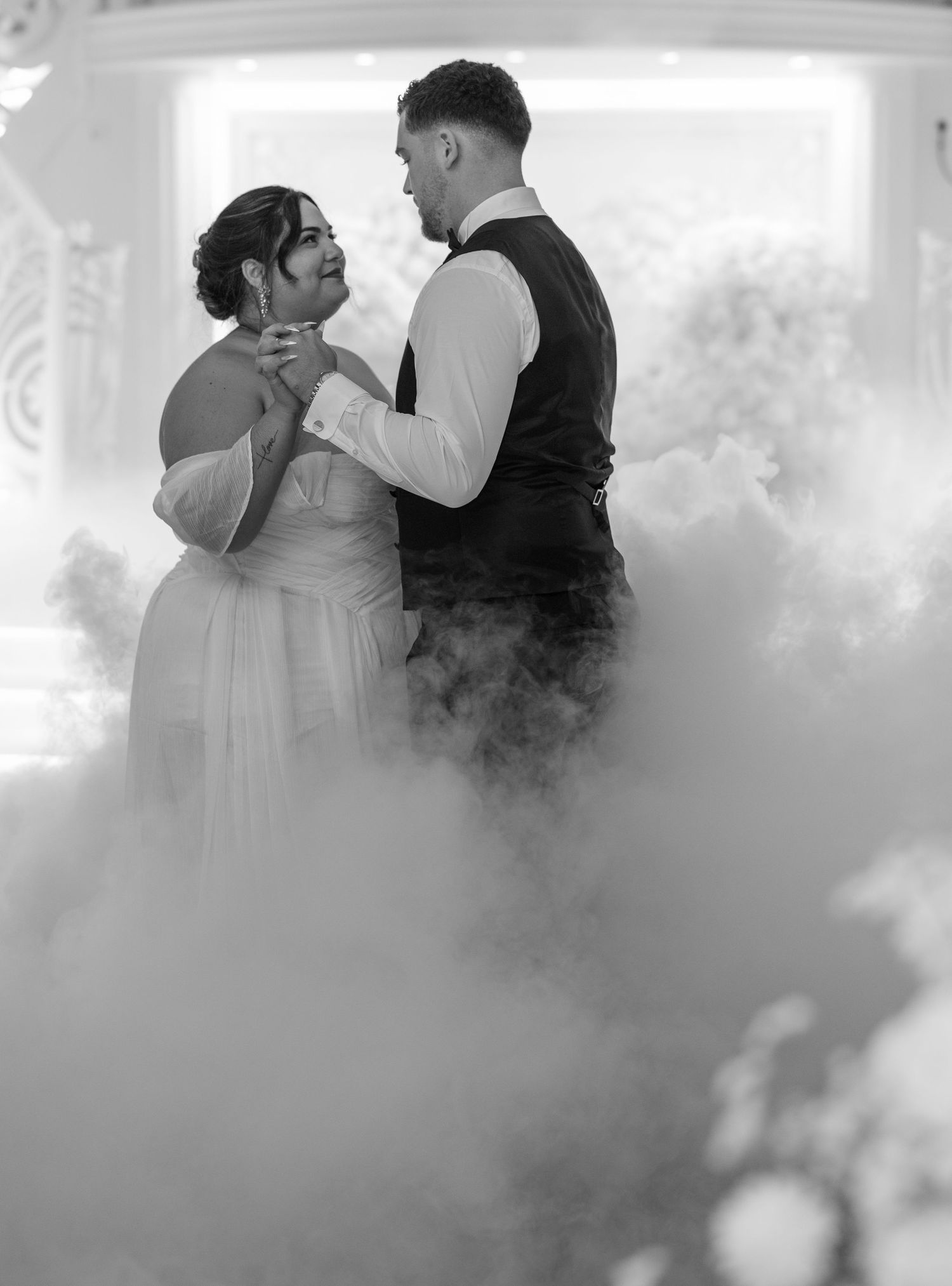 Un couple partage un moment de danse romantique entouré de brouillard atmosphérique sur une piste de danse.