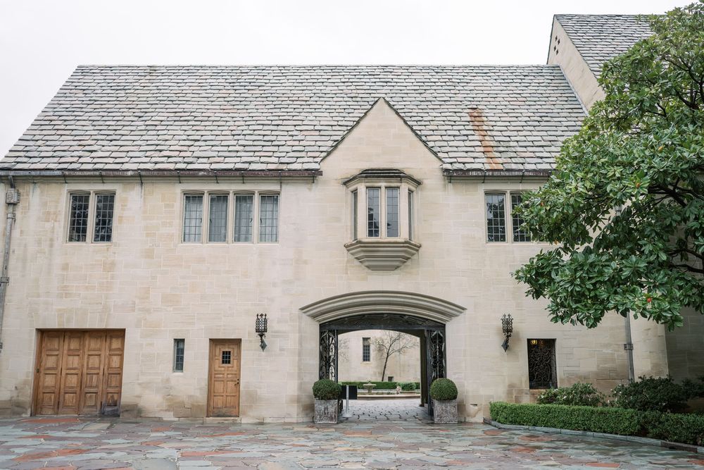 Stone mansion with arched doorways and windows features elegant architectural details and landscaped grounds.