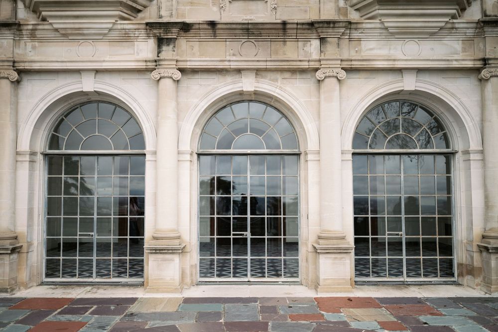 Three large arched windows with ornate classical stone columns and trim on a historic building facade.
