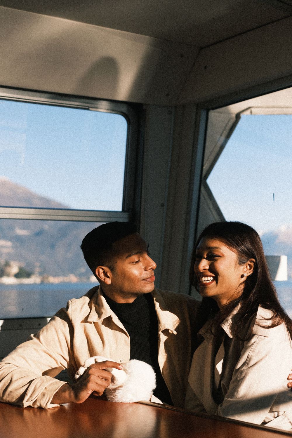 Two people in white clothing share a joyful moment together while sitting in what appears to be a vehicle.
