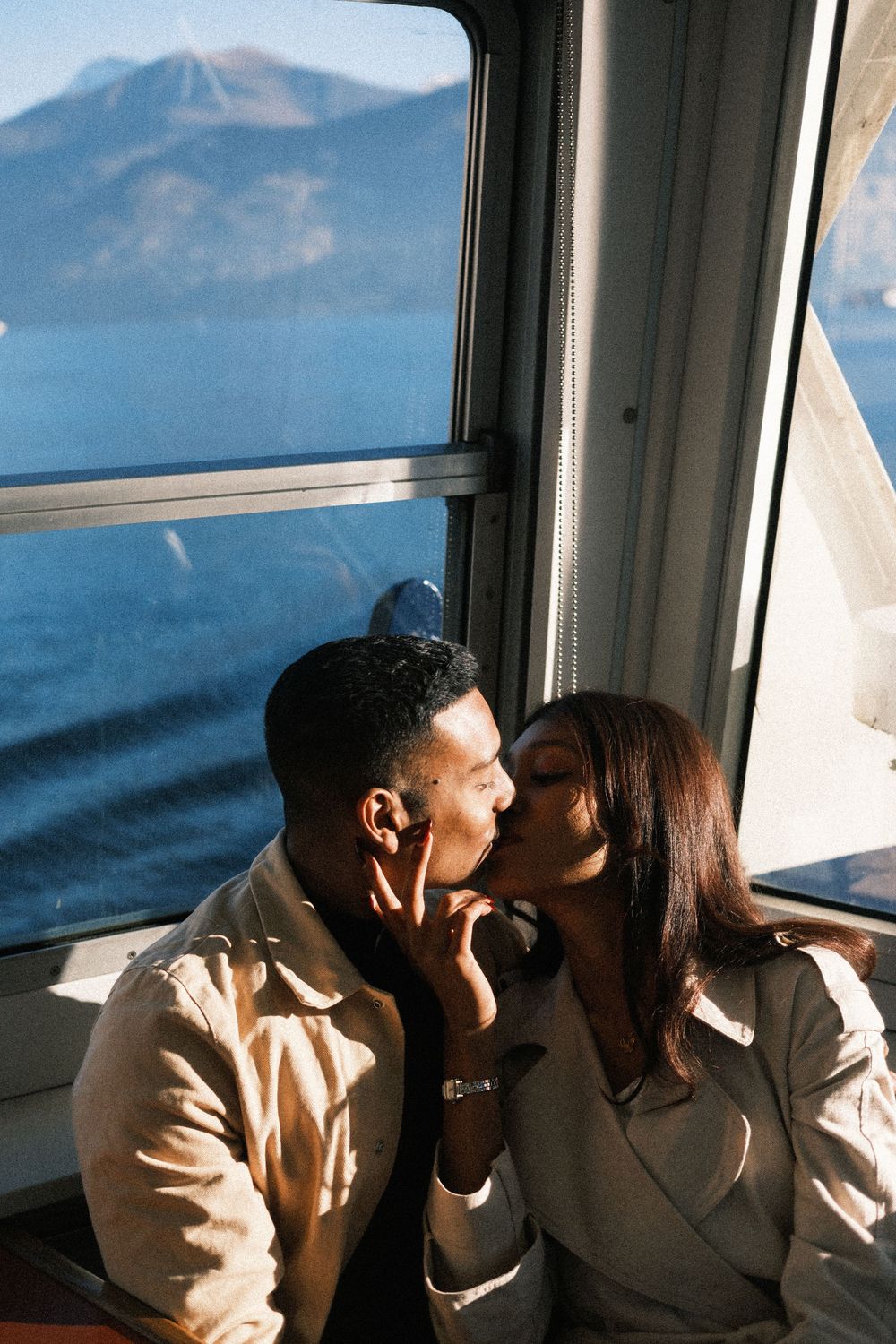 A couple shares an intimate moment in a train car with scenic mountain views through the window.