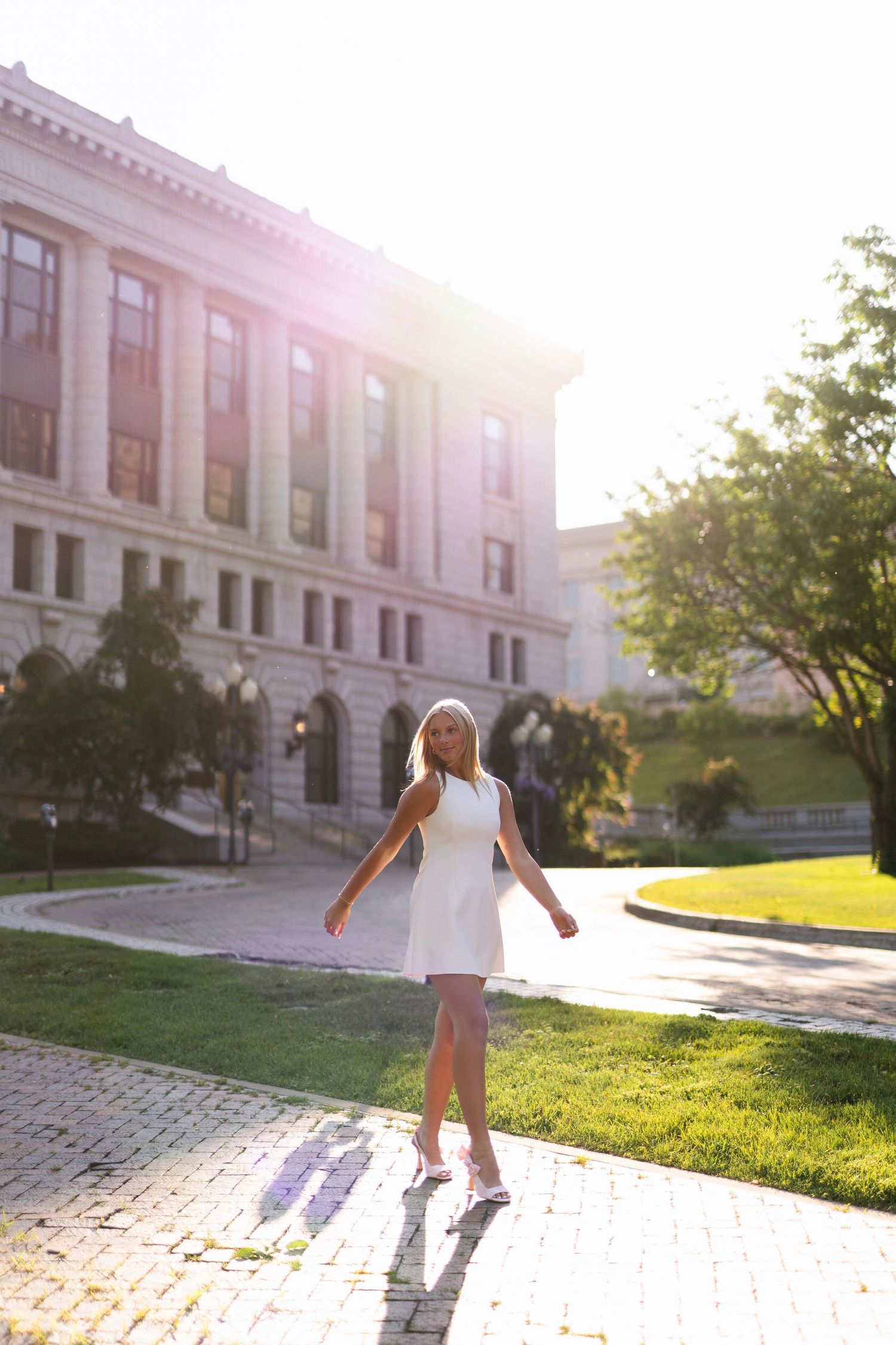 A person dances and twirls in front of a grand historic building during golden hour sunset.