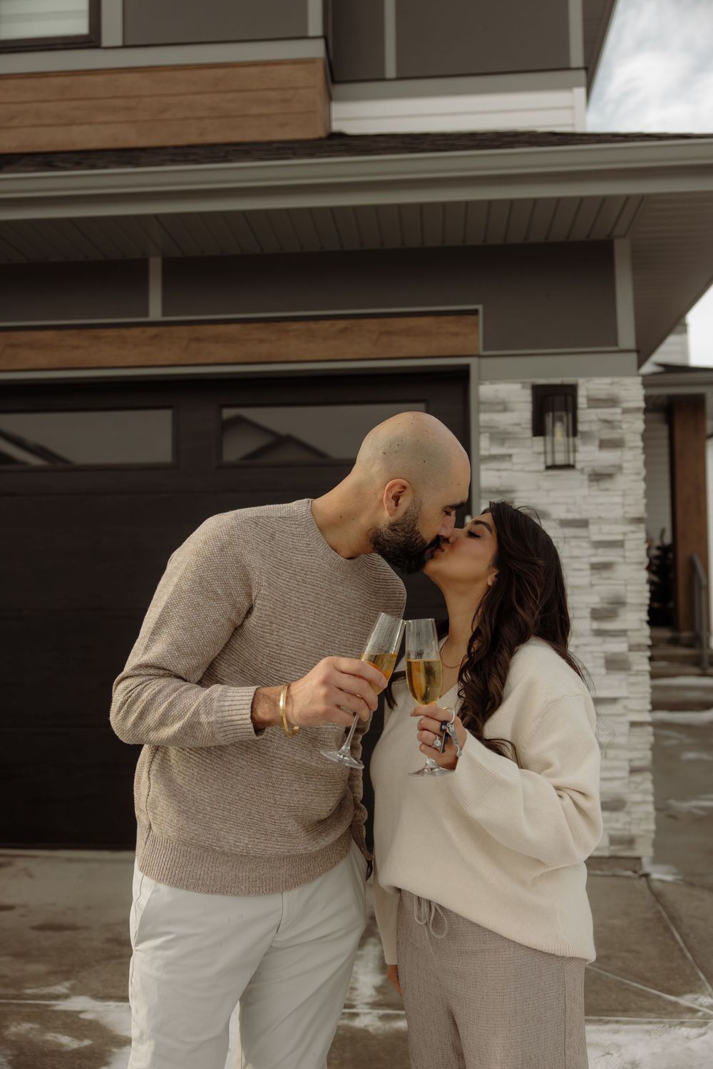 Couple in coordinating cream and beige outfits embracing outdoors.