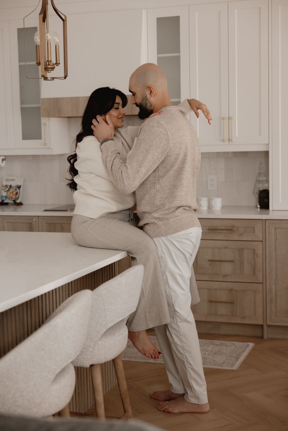 Playful dance sequence of a couple in cozy neutral outfits against white kitchen cabinets.