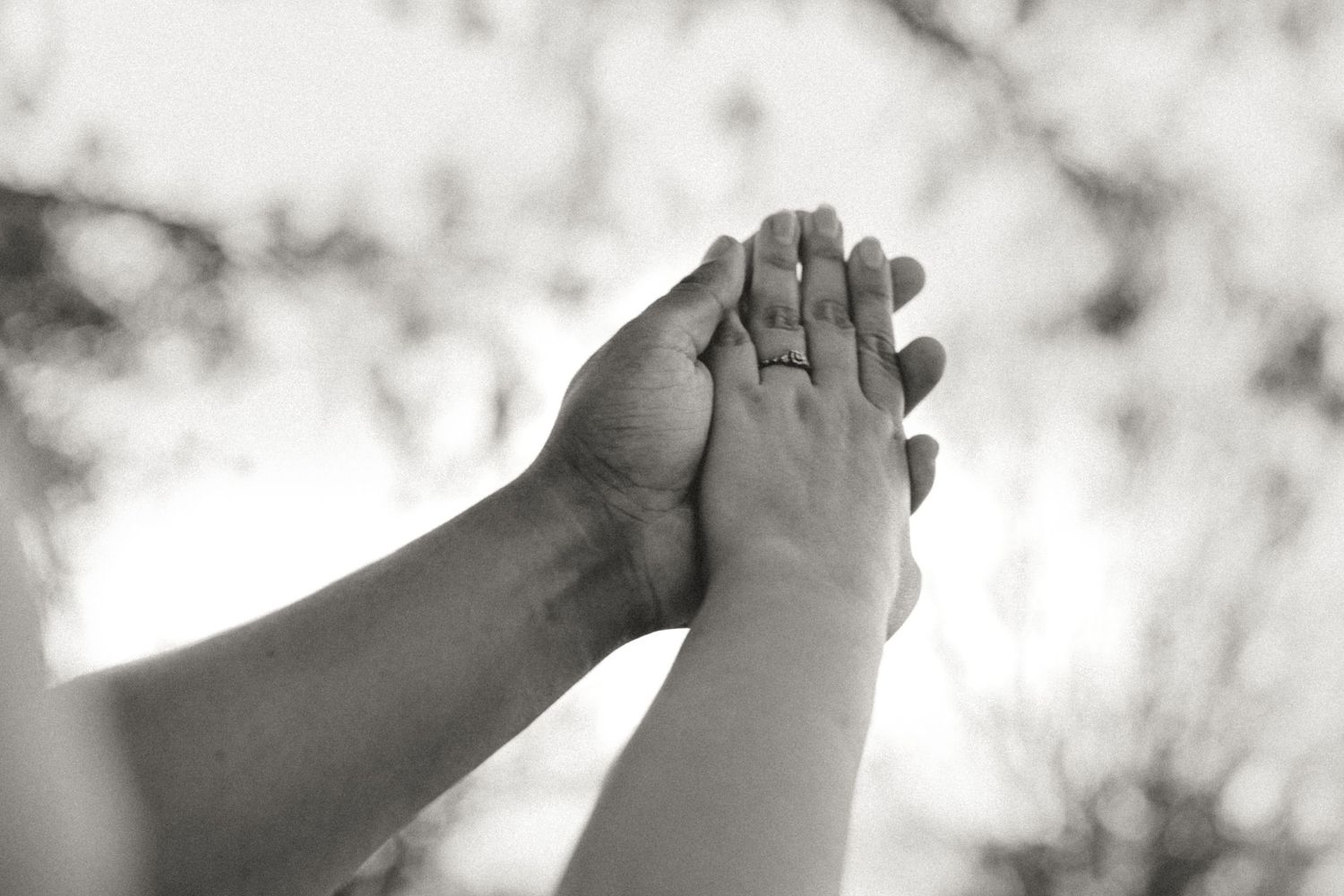 Man holding womans hand, showing engagement ring.