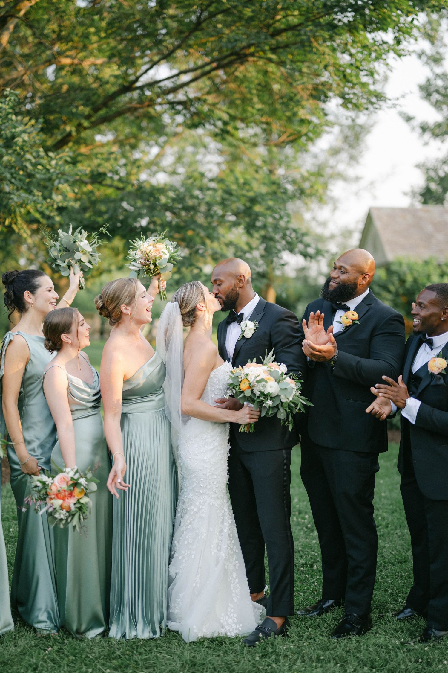 Wedding party celebrates while walking down a tree-lined path at an outdoor garden ceremony. - Elawa Farm