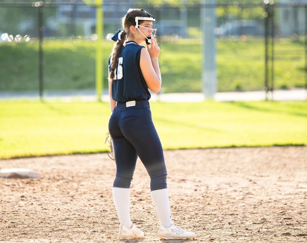 Softball players positioned on dirt field during game.