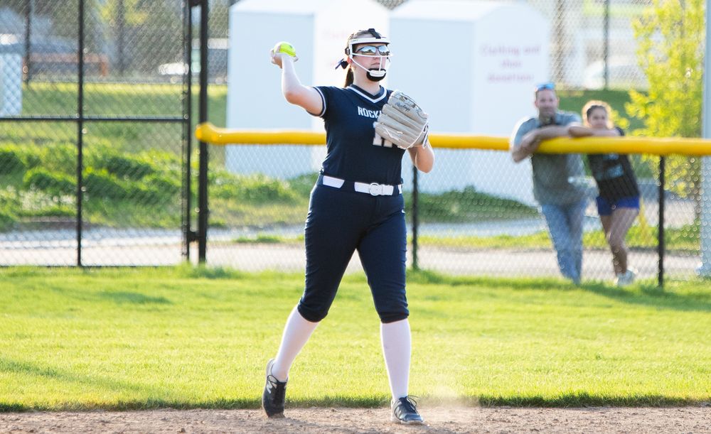 Softball players in action on a sunny field during a game.