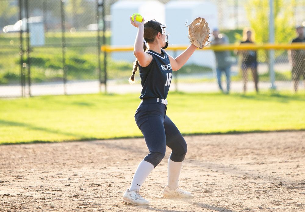Softball players fielding and running on a dirt diamond during gameplay.