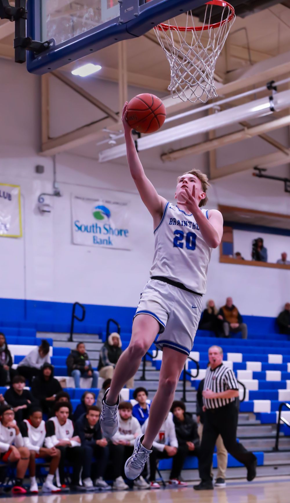 Basketball player executing layup drill in school gymnasium.