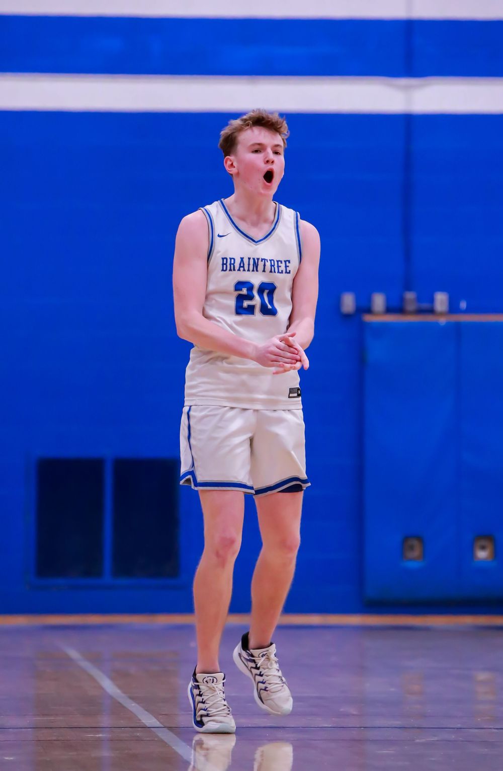 Basketball players in white uniforms on a blue court during a game.
