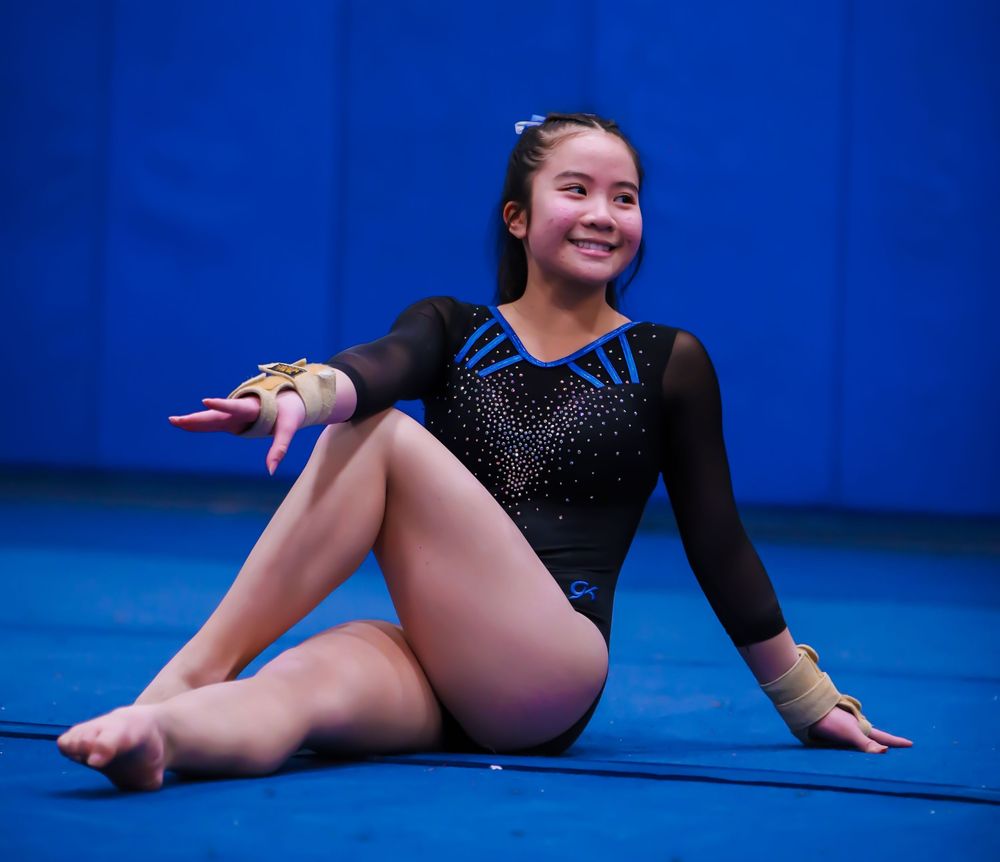 Gymnasts performing floor routines against blue backdrop in competition.