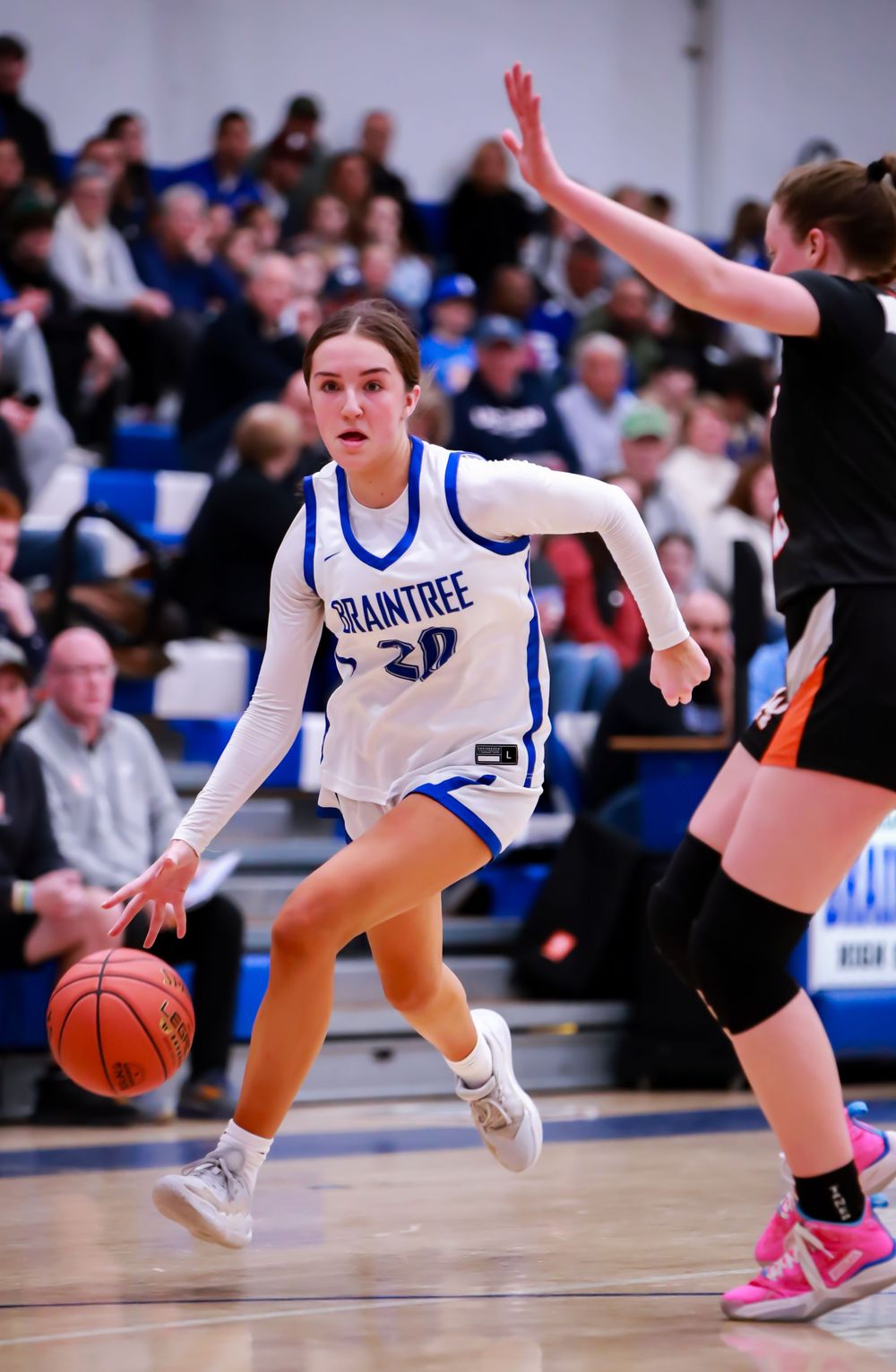 Basketball player in white uniform dribbling past defender during intense game action.