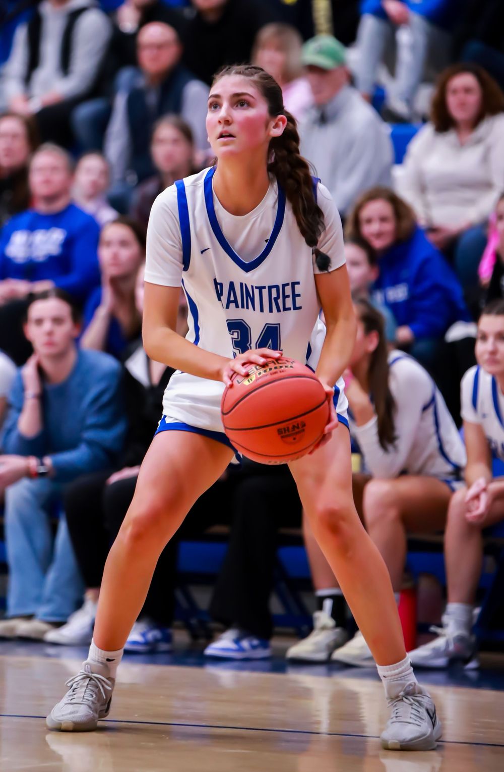 Basketball players in defensive stance during competitive game on indoor court.