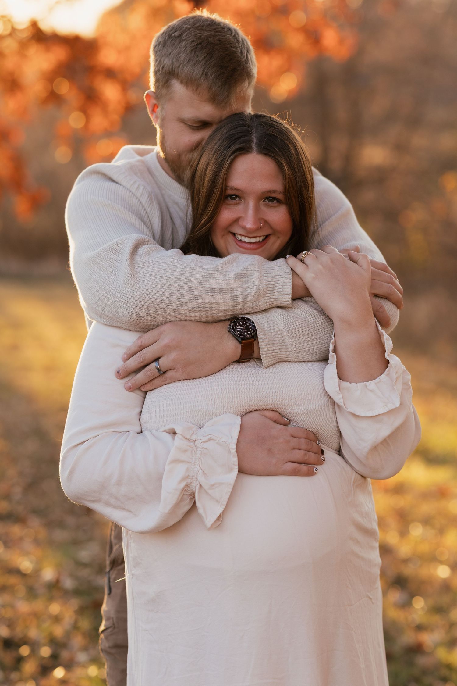 Tender moment captured during autumn maternity photoshoot in warm sunlight.