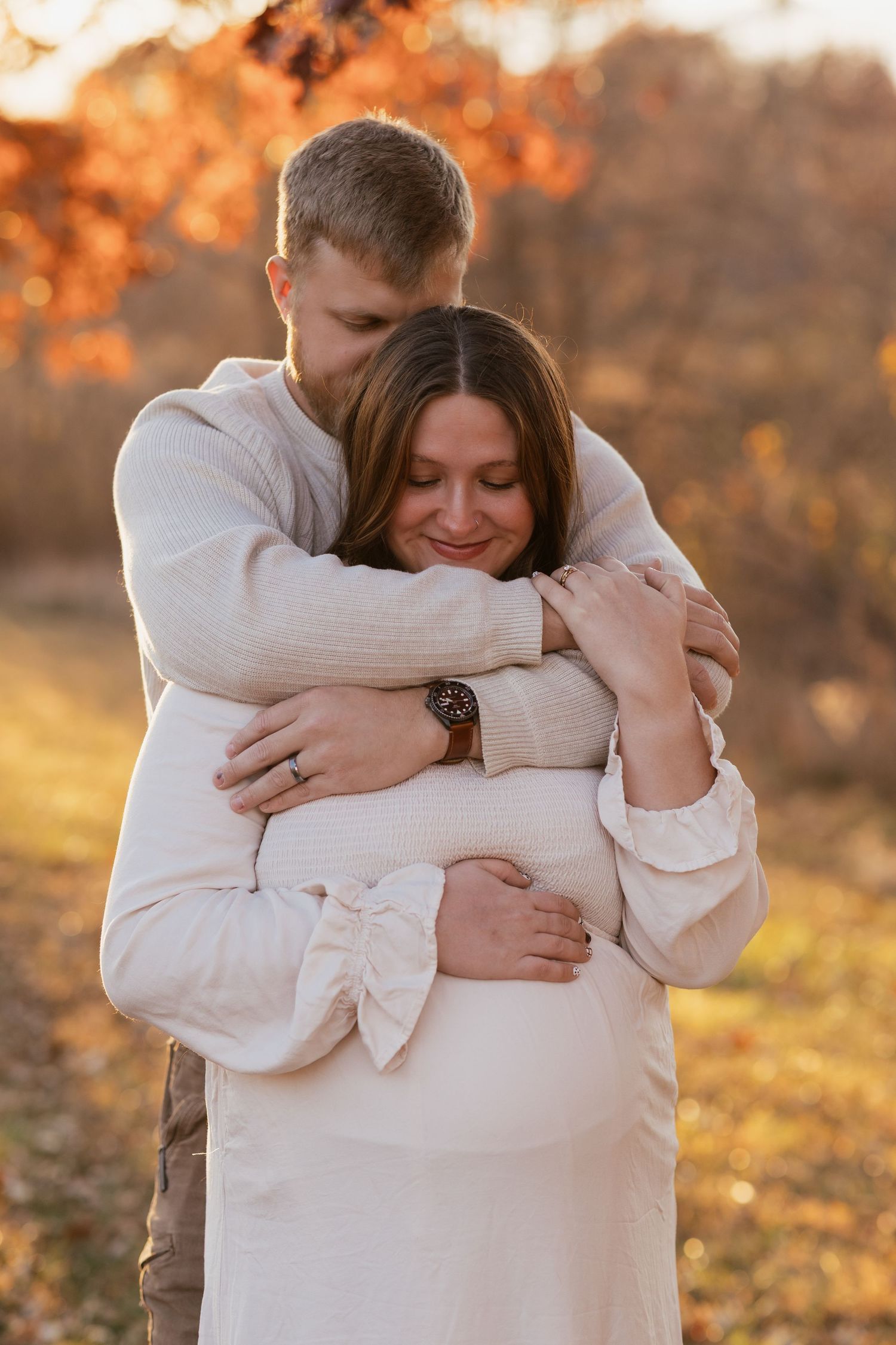 Intimate embrace between couple during golden hour maternity session.