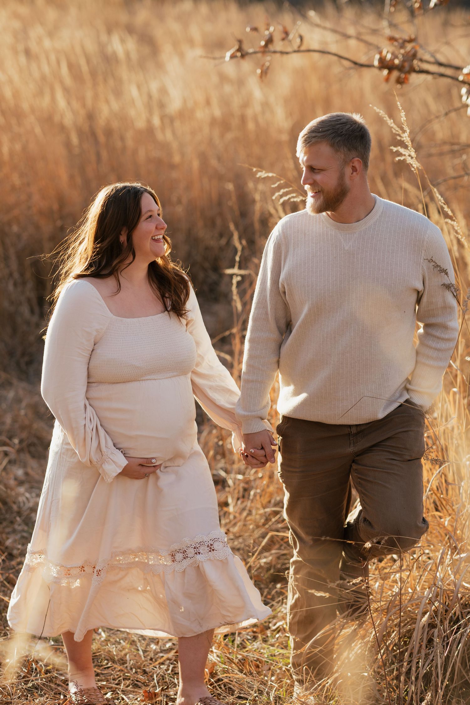 A maternity photo session captures a tender moment between a couple surrounded by autumn wheat fields.