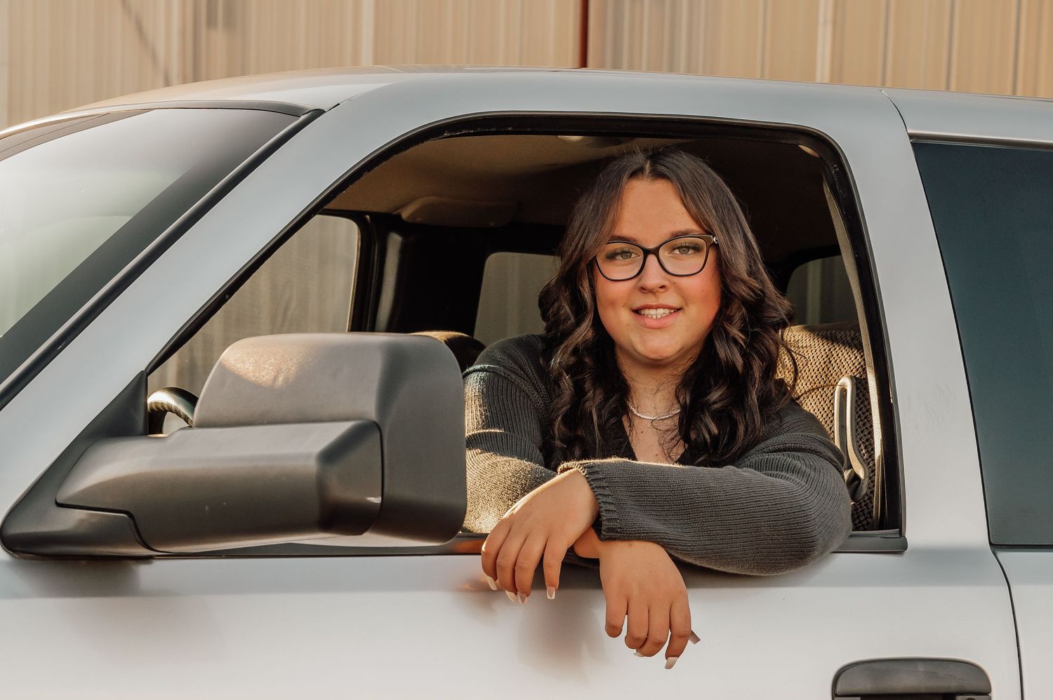 Person sitting in the driver's seat of a silver vehicle with a warm smile.