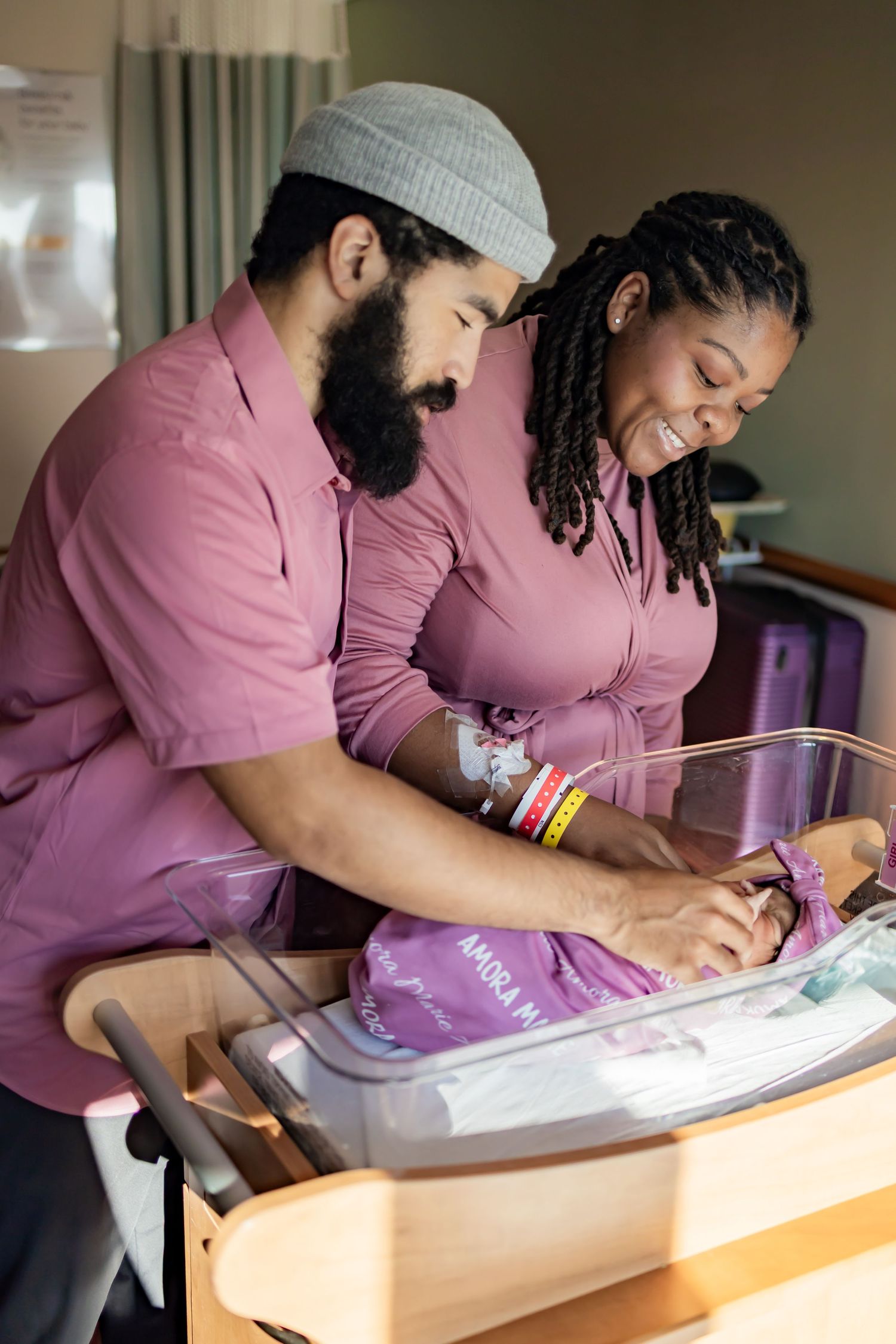 Two healthcare workers in pink scrubs carefully review paperwork together at a desk. Fresh 48 photography newborn session RVA photographer
