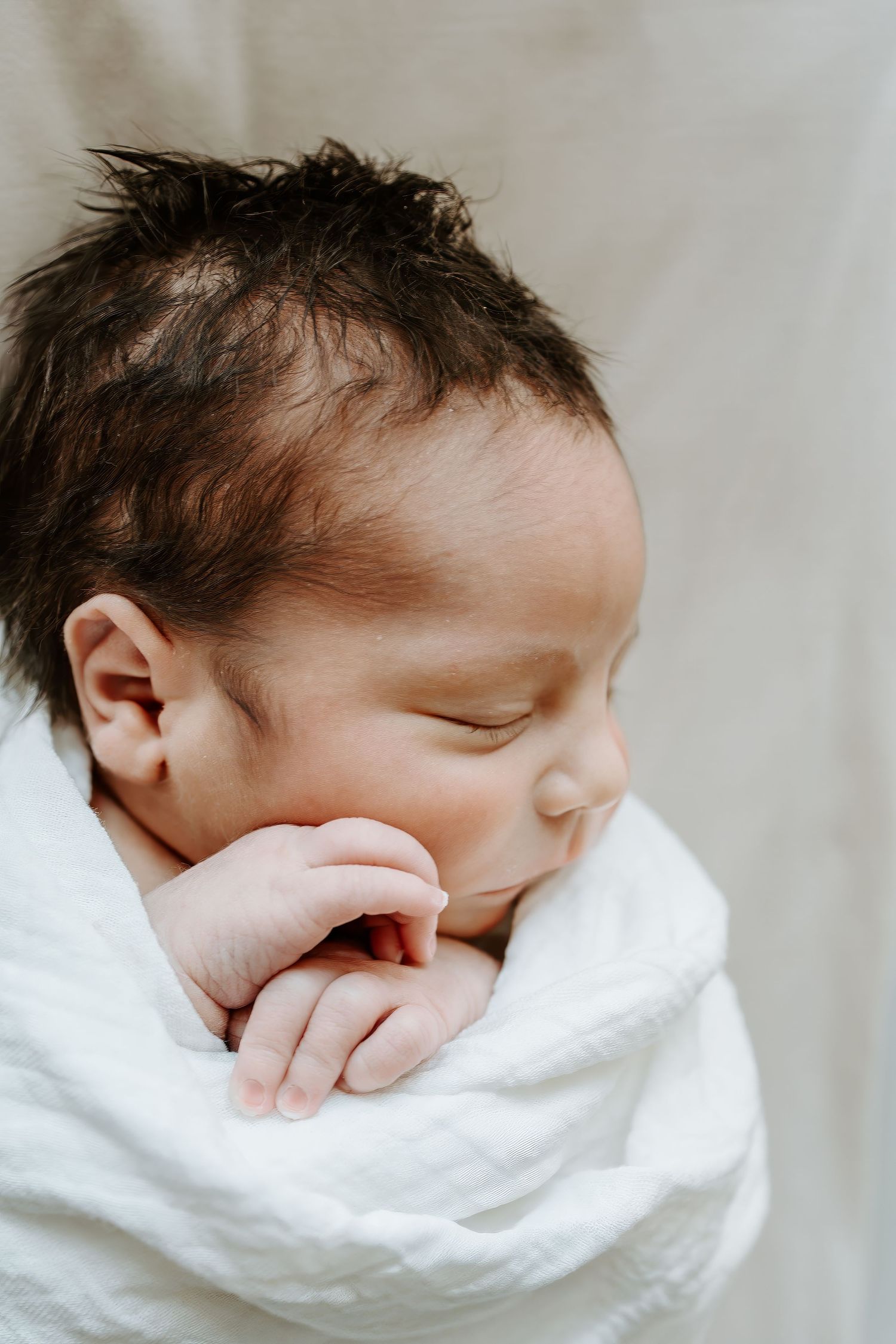 A sleeping newborn baby swaddled in white fabric shown from different angles in a photo collage.