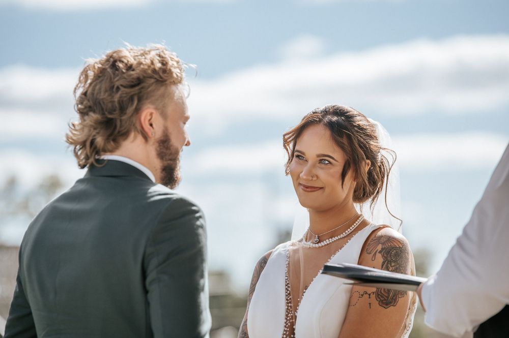 A tender moment captured during an outdoor wedding ceremony under blue skies.