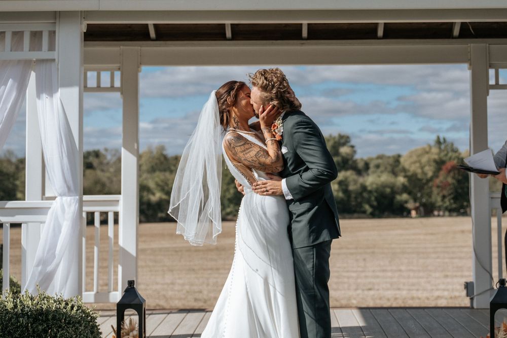 A romantic wedding ceremony moment captured under a white gazebo with scenic countryside views.