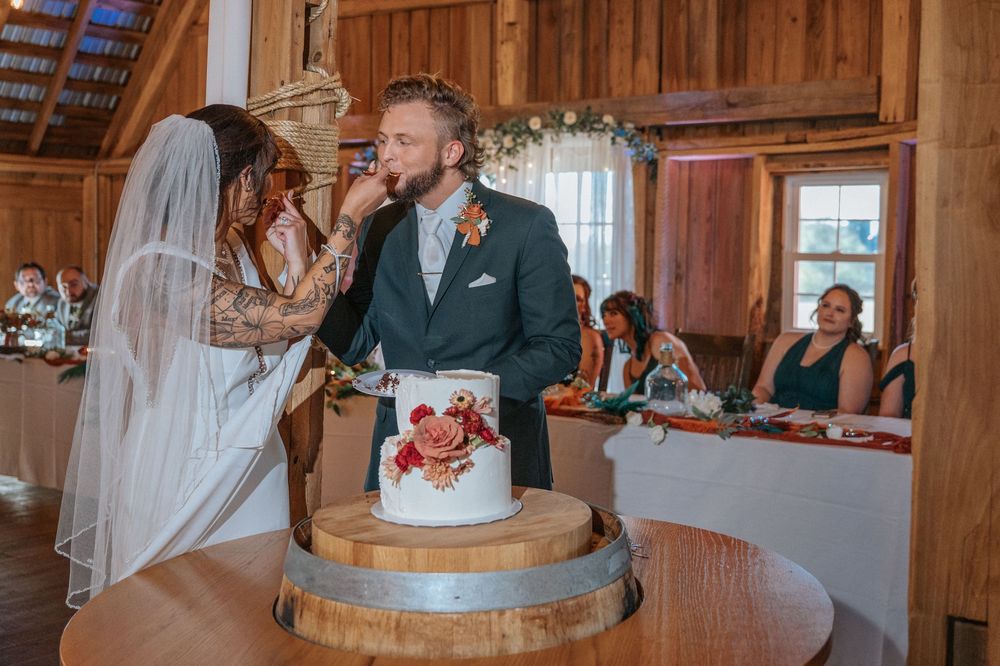 Wedding celebration inside a rustic barn venue with wooden walls and decorative lighting.