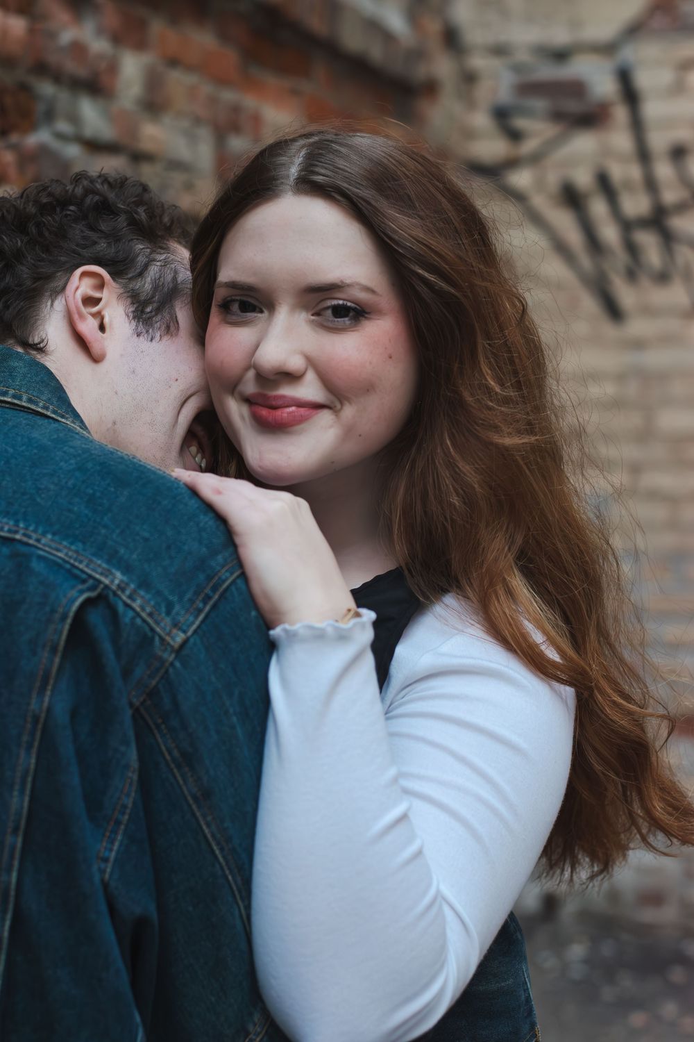 A romantic couple shares intimate moments against a brick wall background.