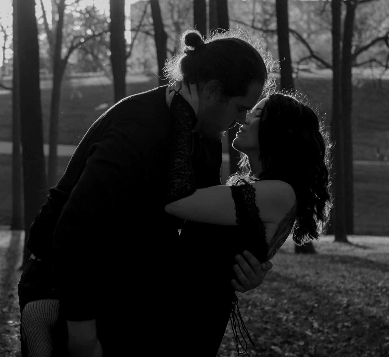 A black and white photo shows two people embracing in silhouette against a backdrop of bare winter trees.