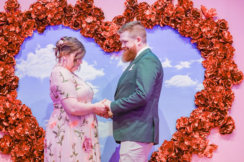 A series of wedding photos under red floral arches showing a couple during their ceremony.