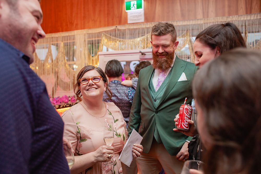 People gathered in a casual indoor setting with wood paneled walls, engaged in conversation and laughter.