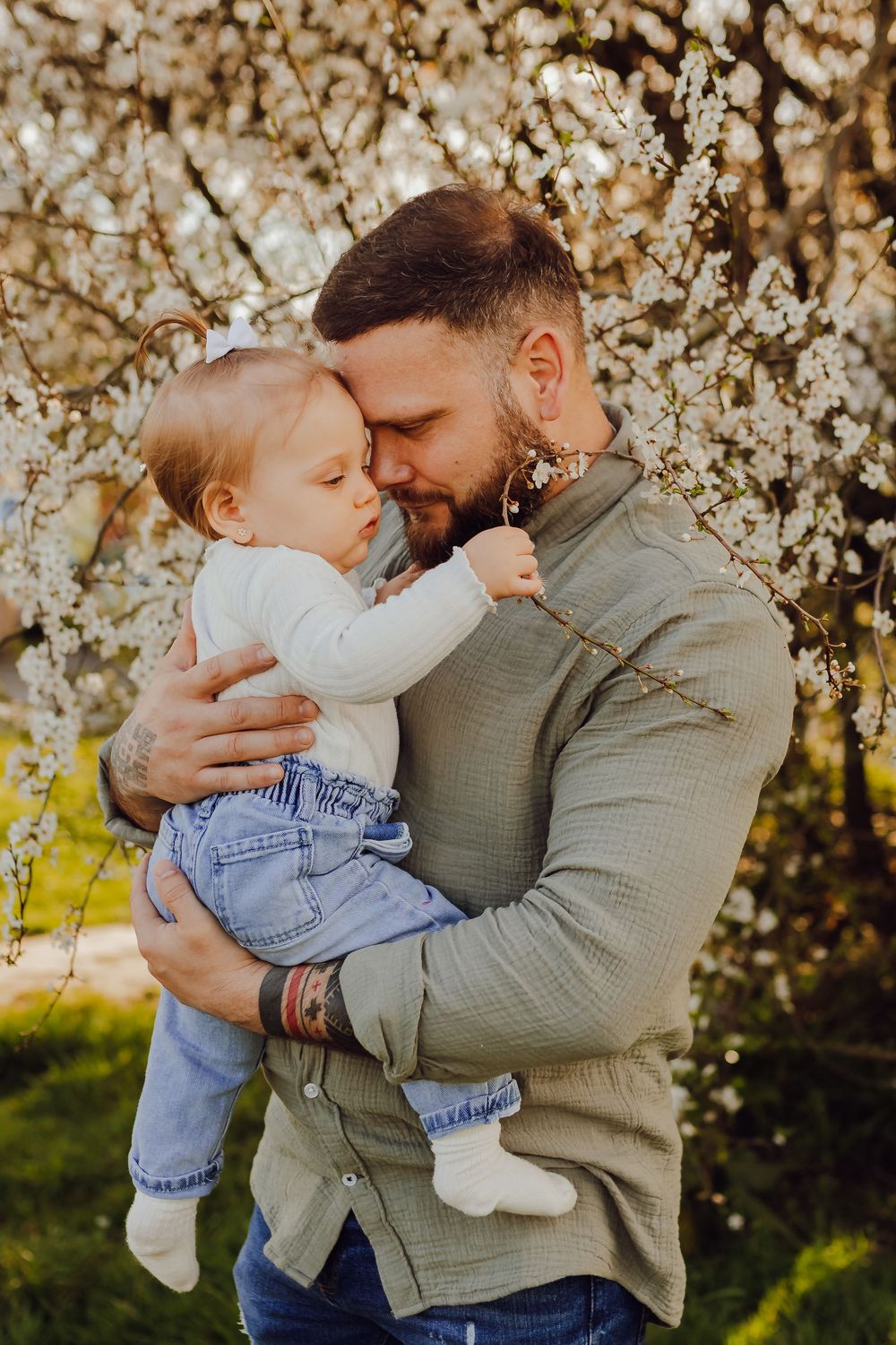 Family cuddling under a flowering tree, soft and natural spring family portraits