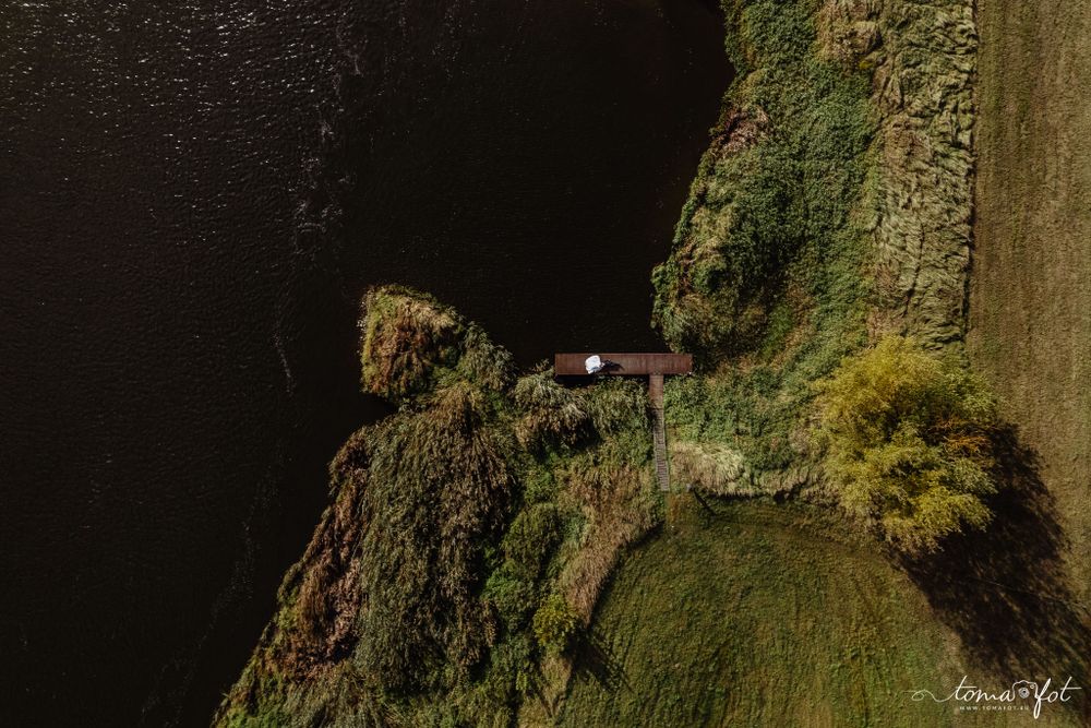 Aerial view of a narrow cliffside road winding along a steep moss-covered coastal cliff at dusk.