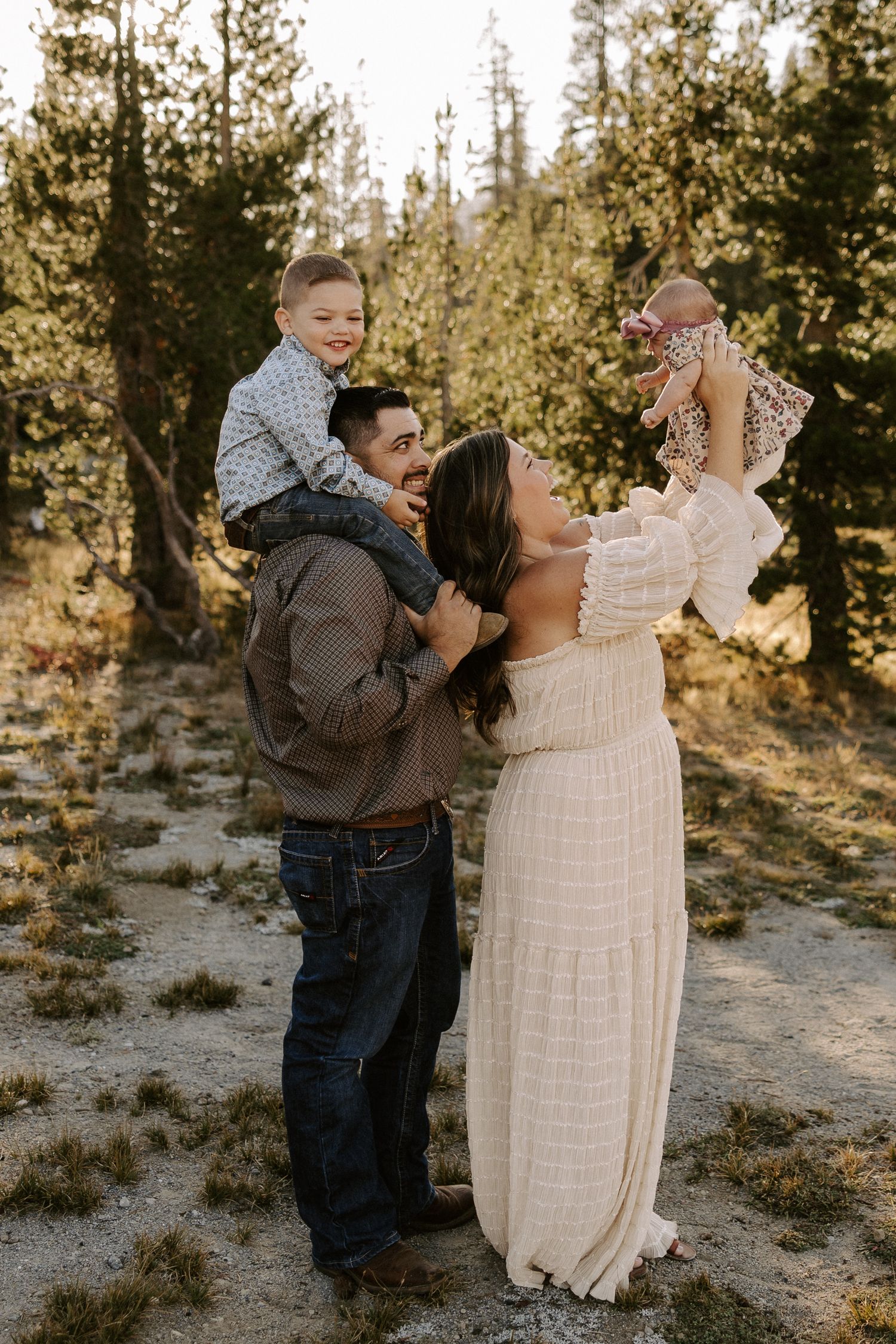 A playful family moment captured in a snowy forest setting during golden hour.