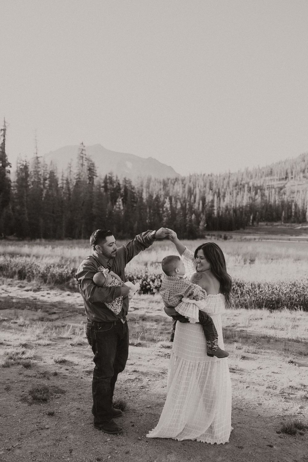 A family shares a tender moment together in a beautiful mountain meadow setting at sunset.