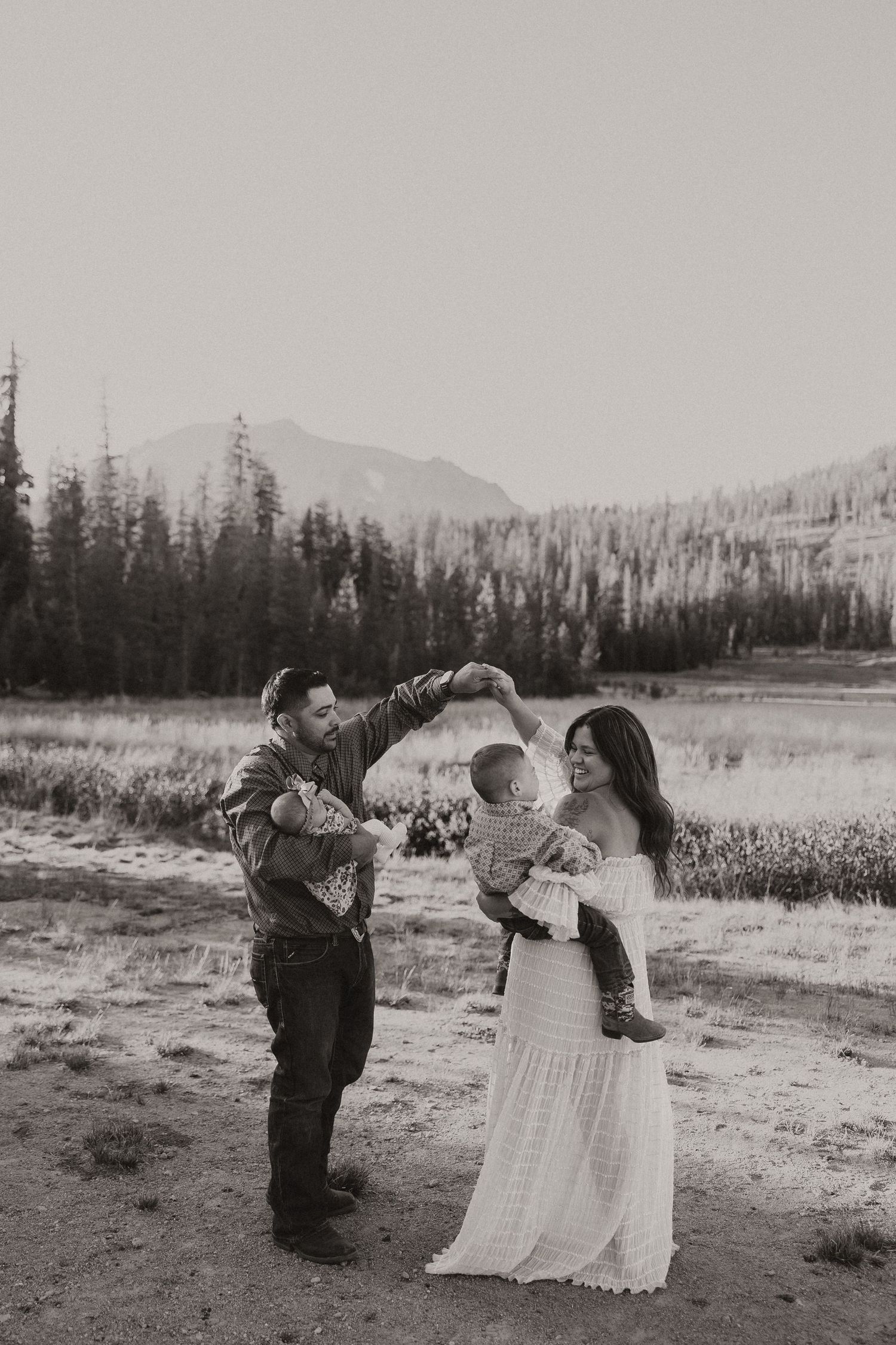 A family shares a tender moment together in a beautiful mountain meadow setting at sunset.