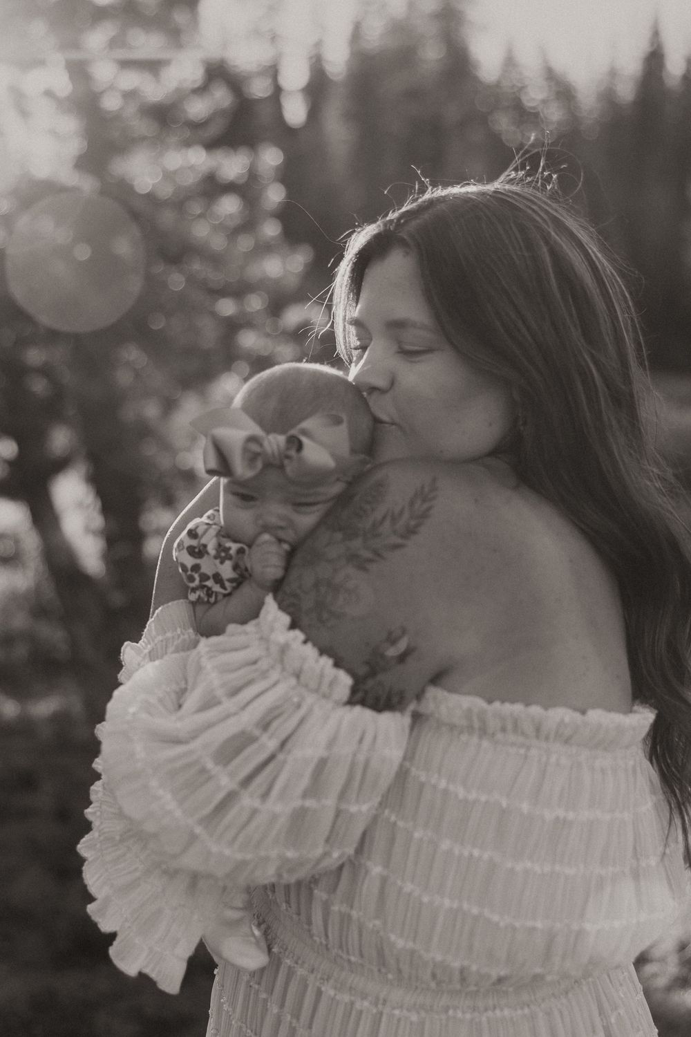 A woman in a white ruffled off-shoulder dress poses in a dreamy black and white outdoor photoshoot.