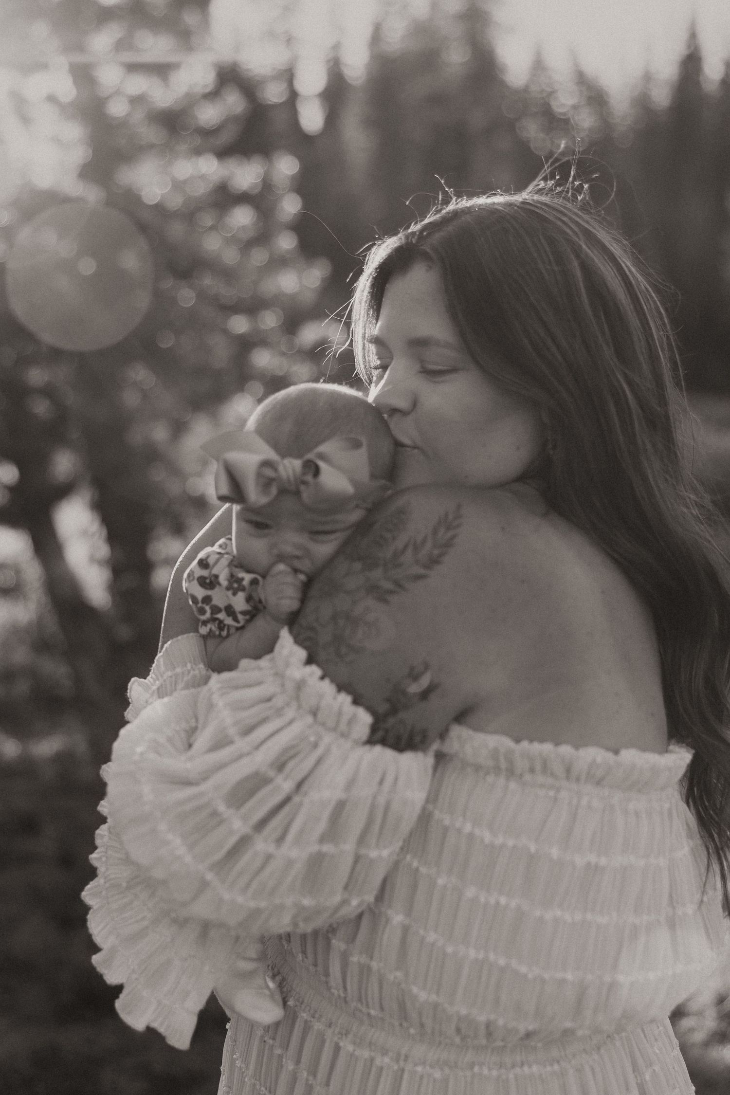 A woman in a white ruffled off-shoulder dress poses in a dreamy black and white outdoor photoshoot.