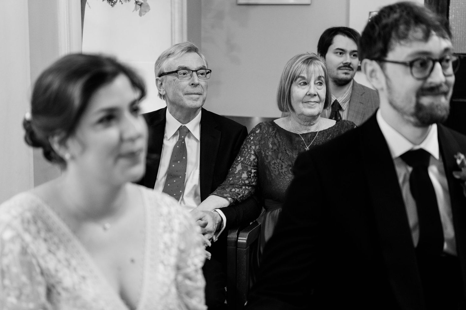 A group of formally dressed guests smile and celebrate at an elegant wedding reception.