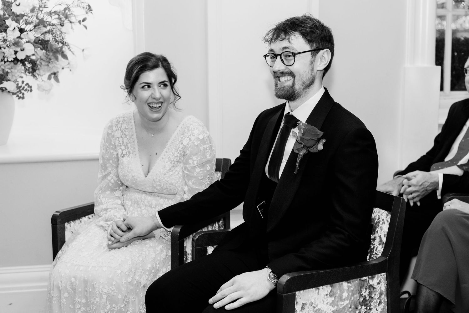 A joyful couple shares a laugh while sitting together during a wedding celebration.